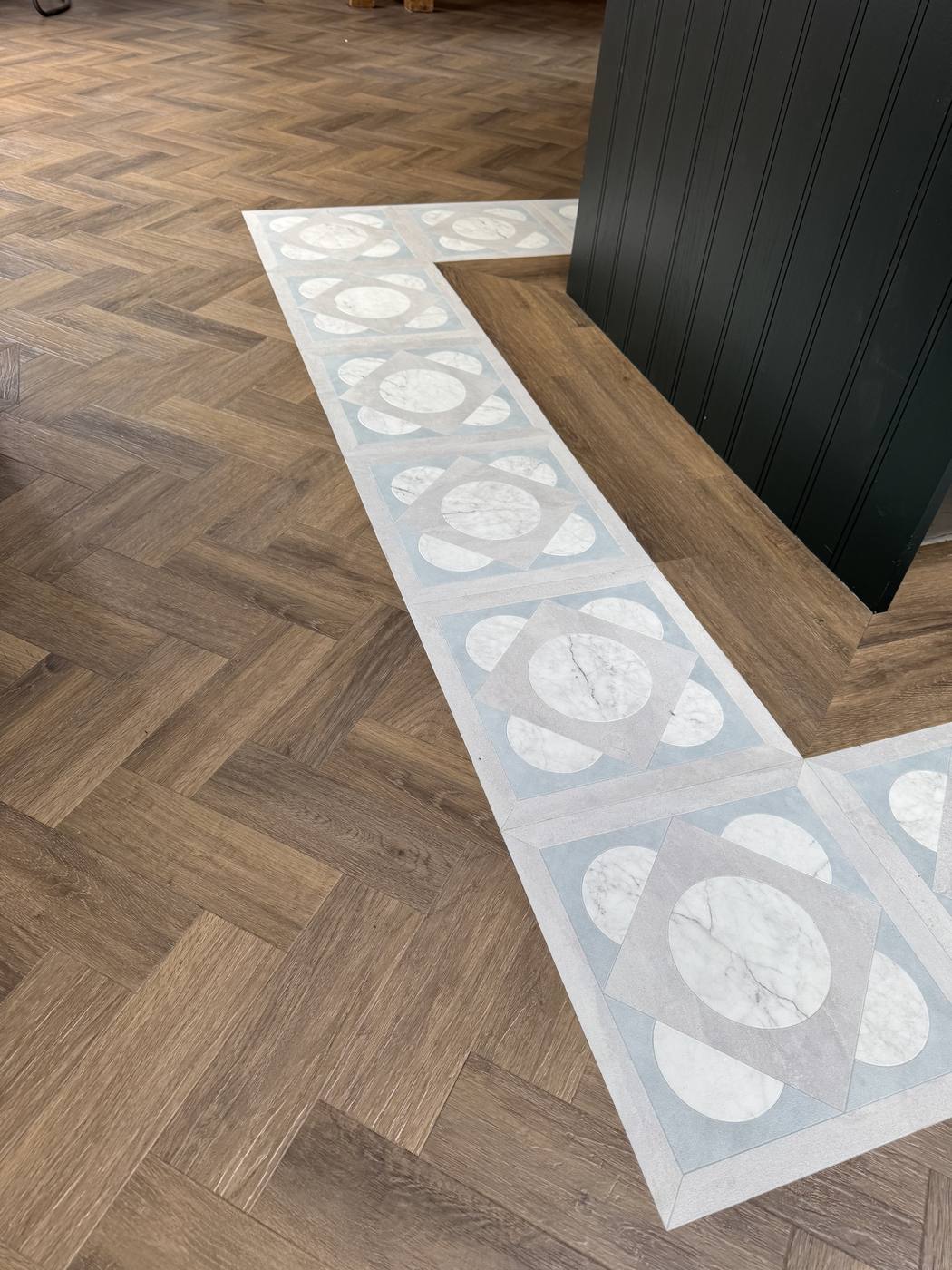 Amtico herringbone LVT with a marble-effect feature border around a kitchen island